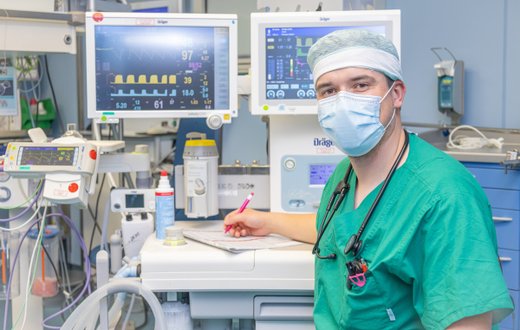 Arzt im OP-Saal mit Überwachungsmonitoren und medizinischer Ausrüstung.