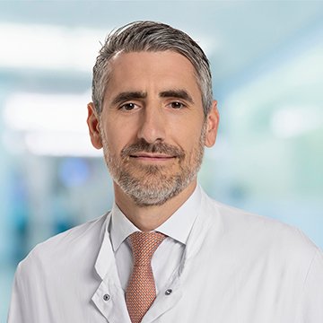 Porträt eines Arztes in weißem Kittel, professionelles Umfeld.