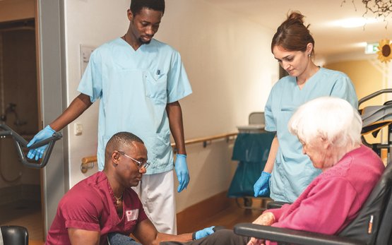 Pflegekräfte betreuen ältere Frau im Martha-Maria Krankenhaus, Zusammenarbeit symbolisierend.